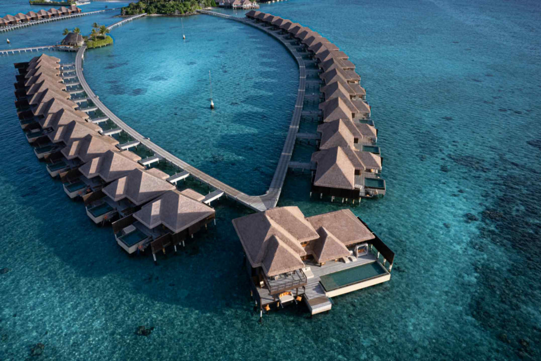 An aerial of the overwater villas at Ayada Maldives above clear shallow water