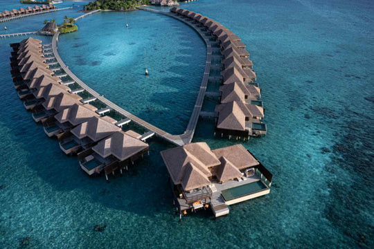 An aerial of the overwater villas at Ayada Maldives above clear shallow water