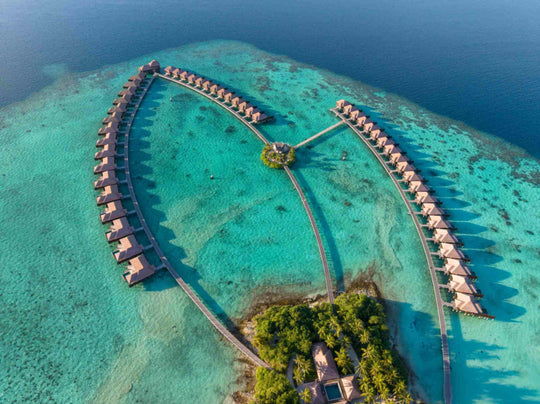 Ayada Maldives from the air, the full loop of overwater villas beside the wooded island