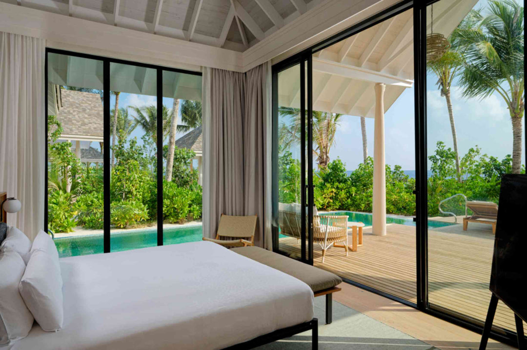 A beach villa bedroom at ananea Madivaru Maldives opening straight on to the pool deck