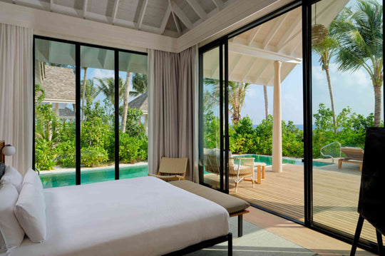 A beach villa bedroom at ananea Madivaru Maldives opening straight on to the pool deck