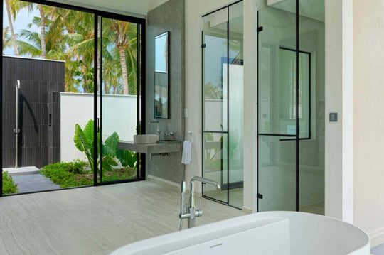An open-air shower and bathroom at a beach villa at ananea Madivaru Maldives, planted with greenery