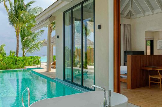 The pool of a beach villa at ananea Madivaru Maldives running alongside the bedroom, palms overhead
