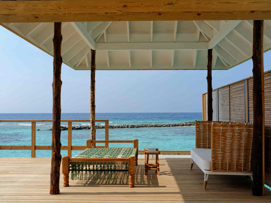 The shaded deck of an overwater villa at ananea Madivaru Maldives looking out over the lagoon to the reef