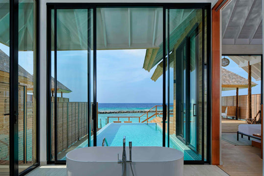 Floor to ceiling glass in an overwater villa at ananea Madivaru Maldives, the pool and open sea beyond