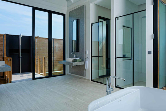 A villa bathroom at ananea Madivaru Maldives, basin and walk-in shower behind black framed glass