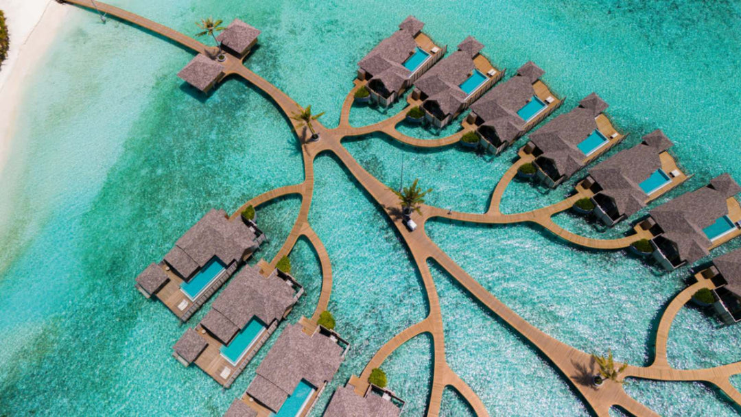 Overwater villas at ananea Madivaru Maldives from the air, branching off a timber walkway over the lagoon