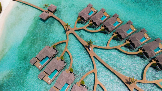 Overwater villas at ananea Madivaru Maldives from the air, branching off a timber walkway over the lagoon