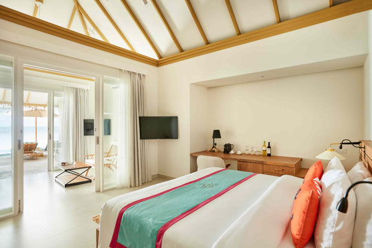 Sun Siyam Iru Veli, Dhaalu Atoll — bedroom under a vaulted ceiling with a desk and doors to a beach terrace