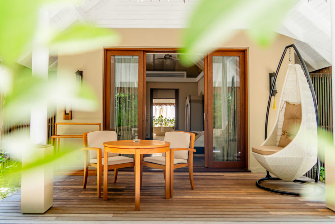 The deck of a garden villa at Ayada Maldives with a dining table and a hanging chair