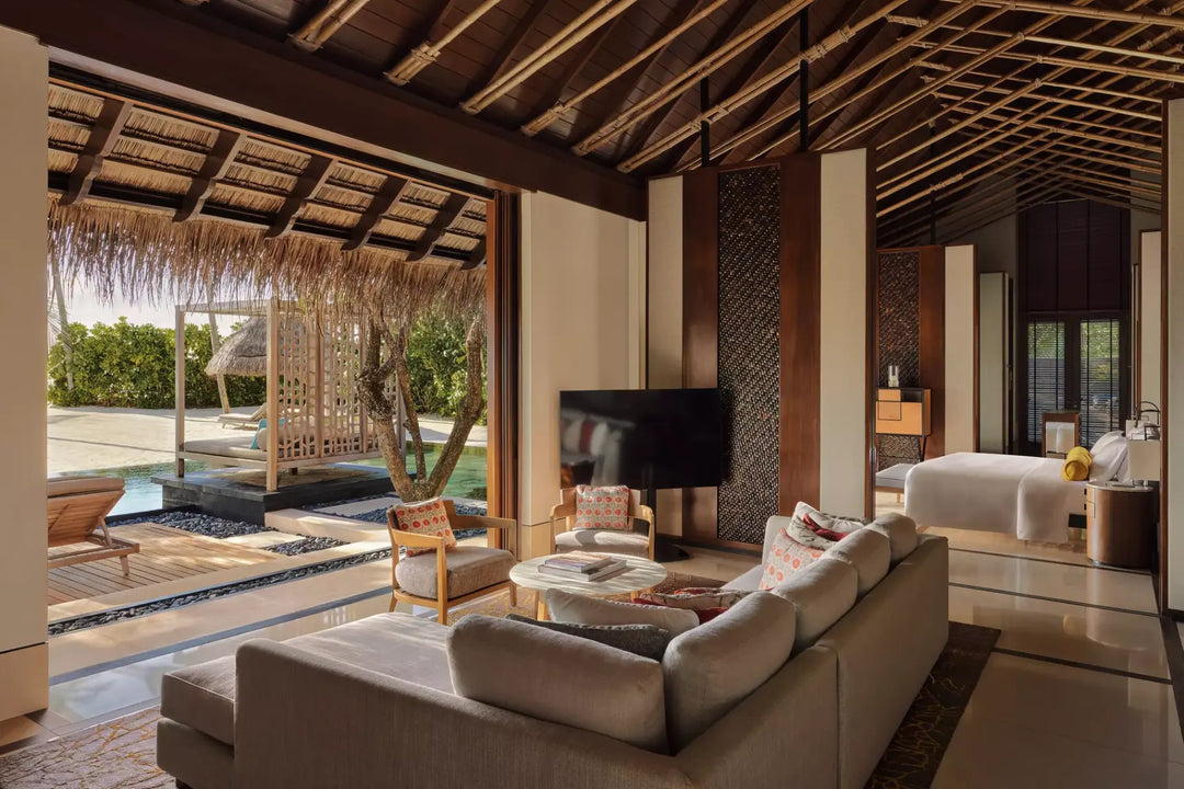 Living area of a One&amp;Only Reethi Rah Grand Beach Villa, opening onto the private pool and a canopied daybed