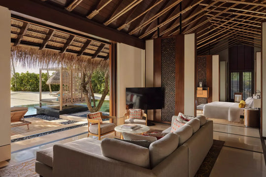 Living area of a One&amp;Only Reethi Rah Grand Beach Villa, opening onto the private pool and a canopied daybed