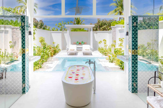 Sun Siyam Iru Veli, Dhaalu Atoll — open-air bathroom looking through to a private pool and loungers, with a flower-strewn tub