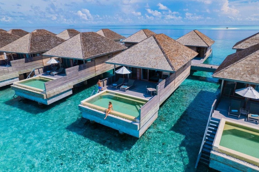 Hurawalhi Maldives, Lhaviyani Atoll — overwater villas from the air, each with a plunge pool set into its deck above the shallow reef