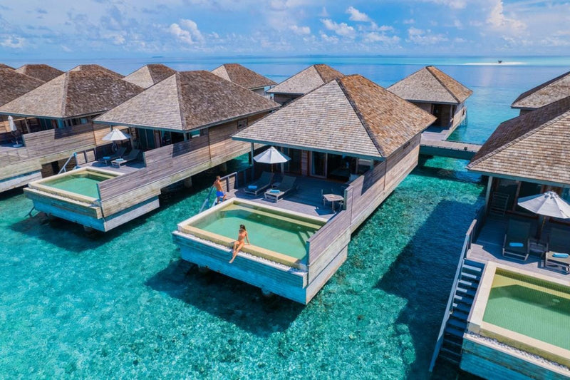 Overwater villas at Hurawalhi Maldives from the air, each with a plunge pool set into its deck above the shallow reef.