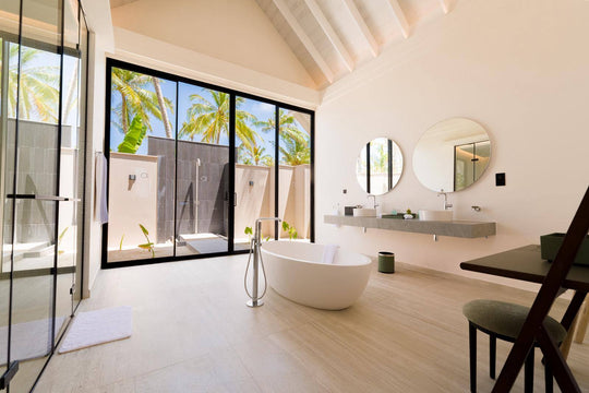 A villa bathroom at ananea Madivaru Maldives, bath and basins open to a planted outdoor shower