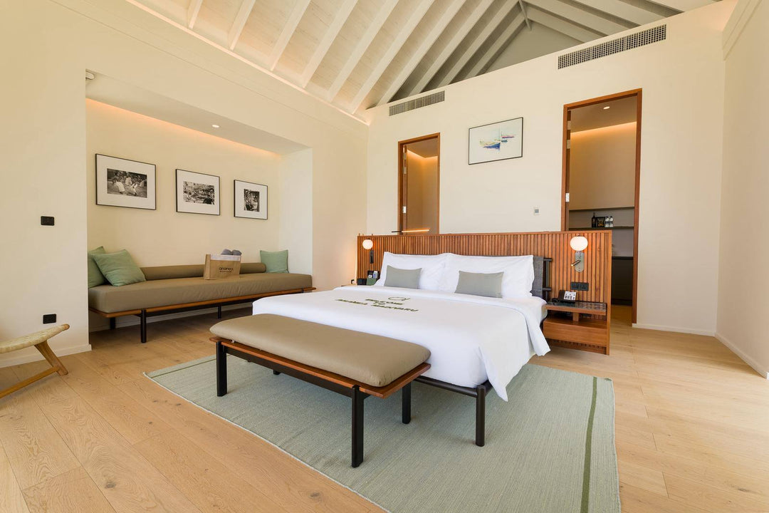A villa bedroom at ananea Madivaru Maldives with a long daybed under framed prints