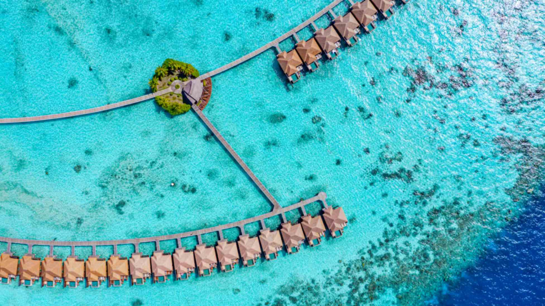 Overwater villas at Ayada Maldives with the small planted islet where the walkways meet