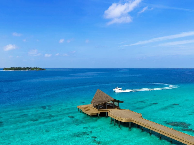 Arrival jetty reaching out over clear shallow water at JW Marriott Maldives Kaafu Atoll Island Resort