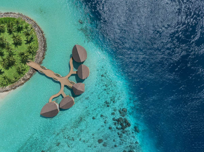 The overwater spa at JW Marriott Maldives Kaafu Atoll seen from the air, its pavilions set over the reef edge