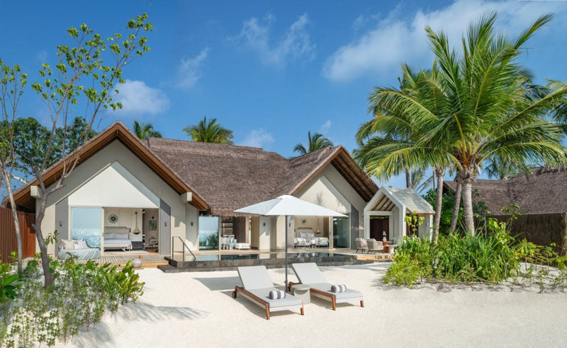 Exterior of a two-bedroom beach villa at JW Marriott Maldives Kaafu Atoll, with loungers on the sand among palms