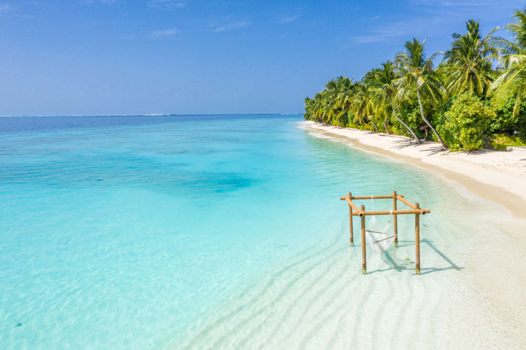The beach at Ayada Maldives with a wooden swing standing in the shallows
