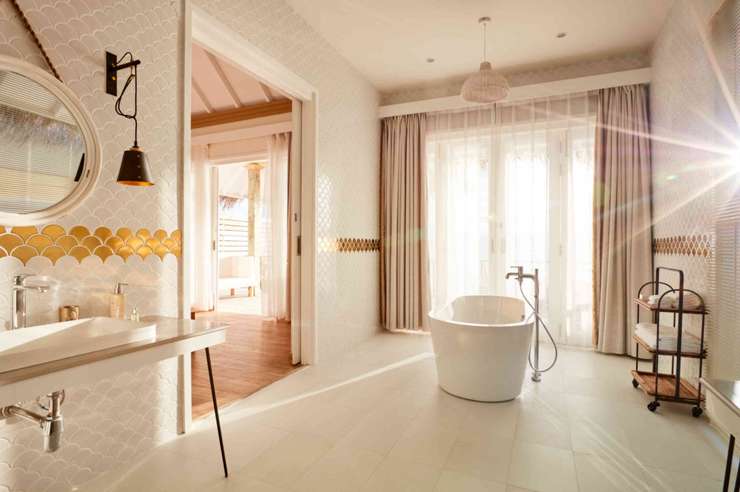 Sun Siyam Iru Veli, Dhaalu Atoll — bathroom with a gold fish-scale tile band, tub and twin basin, bedroom beyond