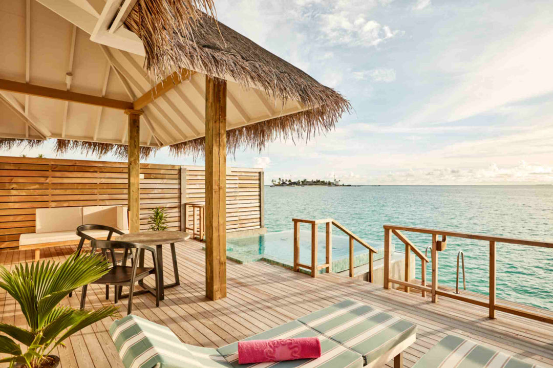 Sun Siyam Iru Veli, Dhaalu Atoll — overwater deck under a thatched shade, lounger and pool at the lagoon edge