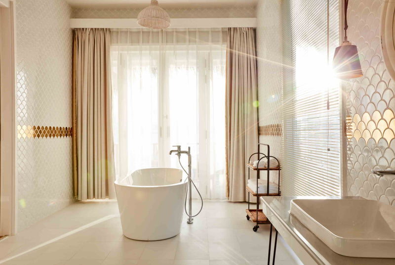 A bathroom at Sun Siyam Iru Veli with a freestanding tub in full sunlight beside a twin basin.