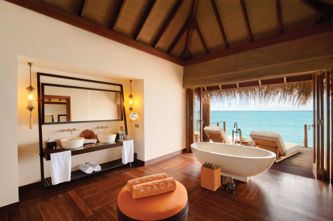 An Ocean Villa bathroom at Ayada Maldives, tub set beside doors open to the lagoon
