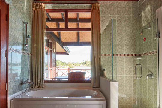 Sun Siyam Olhuveli, South Malé Atoll — corner bath by the window with a glass shower alongside