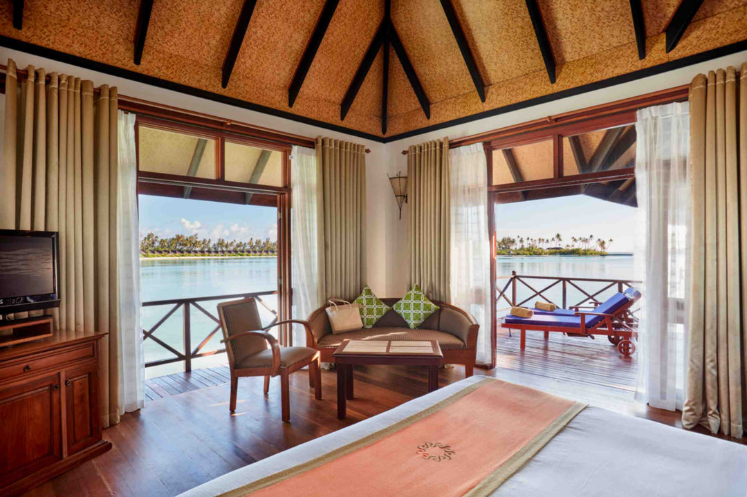 Sun Siyam Olhuveli, South Malé Atoll — water villa bedroom and sitting area with doors onto the deck