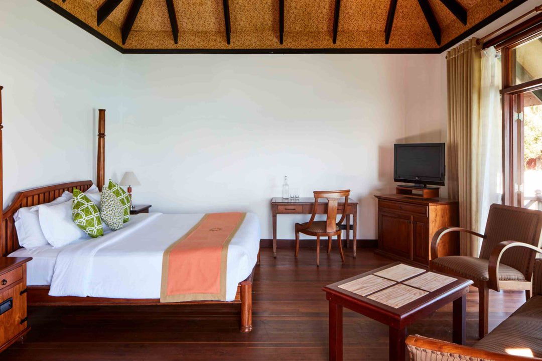 Sun Siyam Olhuveli, South Malé Atoll — water villa bed with a coral runner on a timber floor