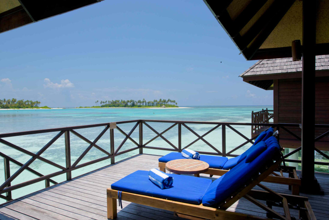 Sun Siyam Olhuveli, South Malé Atoll — sun loungers on a water villa deck looking across the lagoon to a neighbouring island