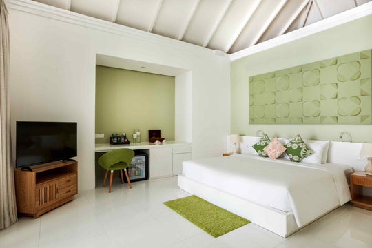 Sun Siyam Olhuveli, South Malé Atoll — Grand Beach Suite bedroom with a padded green headboard and a desk