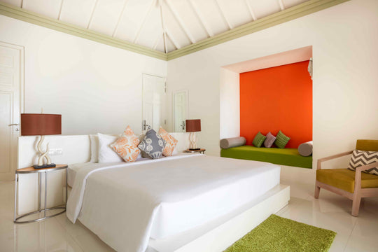 Sun Siyam Olhuveli, South Malé Atoll — beach villa bedroom with an orange feature wall and a green window seat