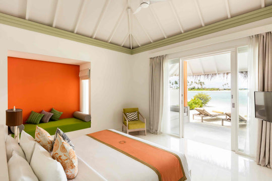 Sun Siyam Olhuveli, South Malé Atoll — beach villa bedroom with doors open to loungers on the sand