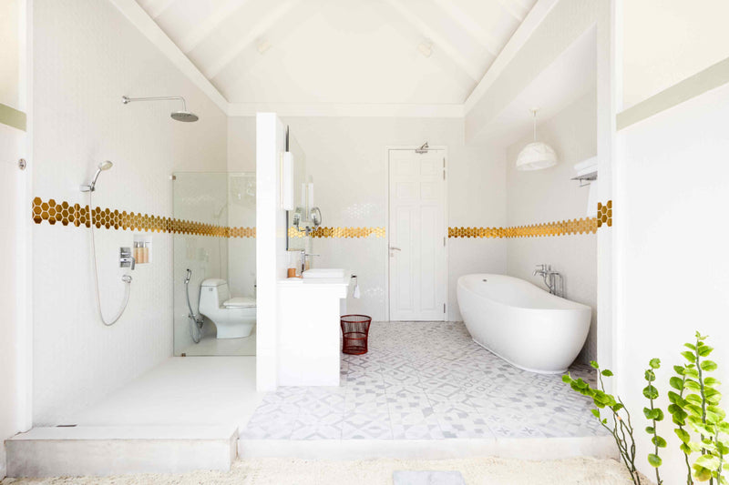 A beach villa bathroom at Sun Siyam Olhuveli with a freestanding bath and a gold mosaic band.