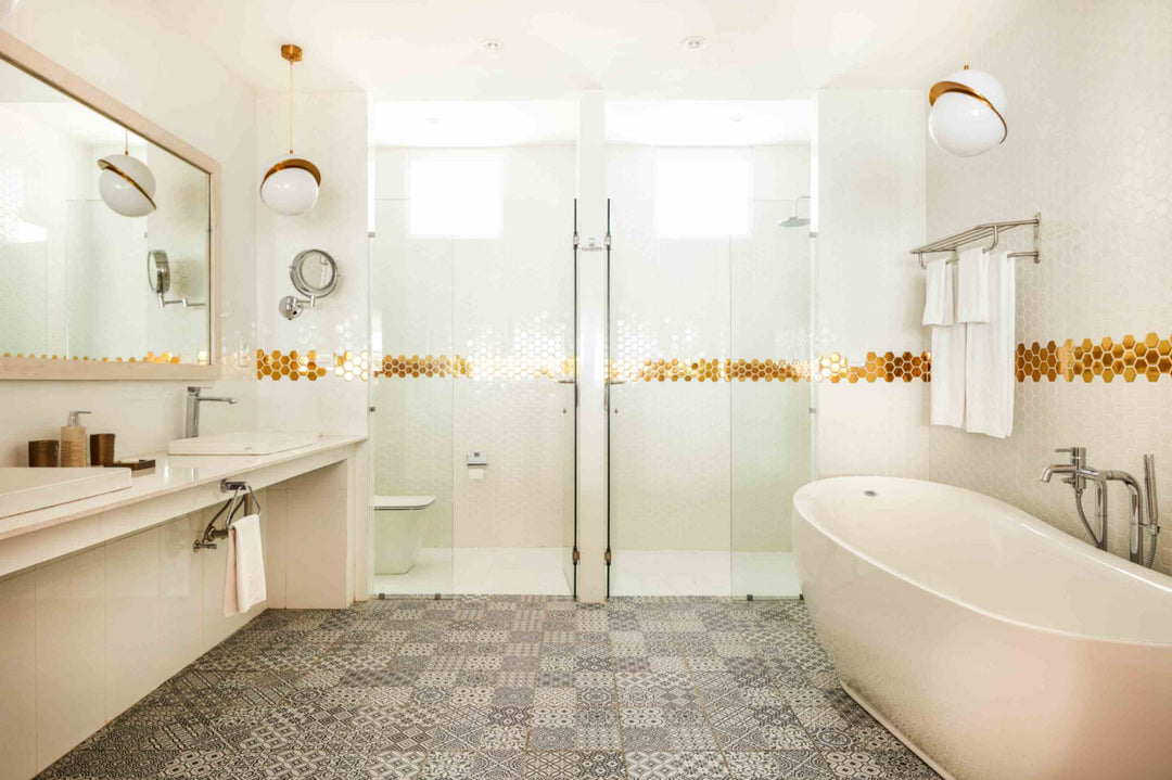 Sun Siyam Olhuveli, South Malé Atoll — water villa bathroom with a freestanding bath, twin basins and a gold mosaic band