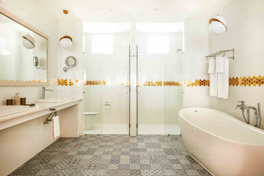 Sun Siyam Olhuveli, South Malé Atoll — water villa bathroom with a freestanding bath, twin basins and a gold mosaic band