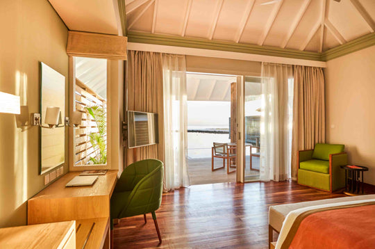 Sun Siyam Olhuveli, South Malé Atoll — water villa interior with a desk and doors onto the deck