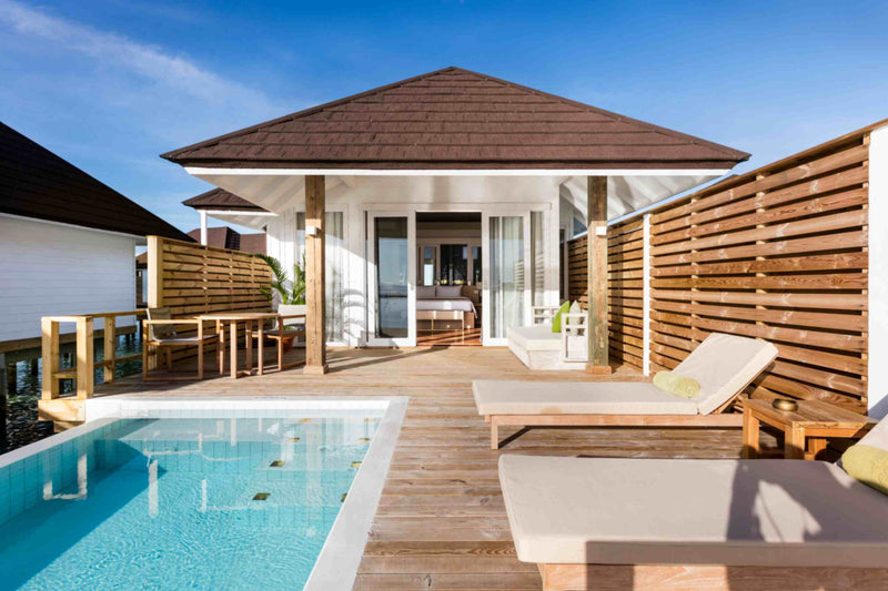 An overwater villa at Sun Siyam Olhuveli with a private pool and loungers on the deck.