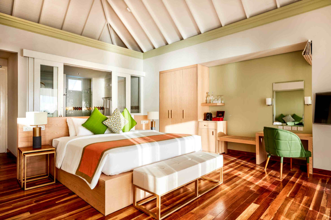 Sun Siyam Olhuveli, South Malé Atoll — Water Villa bedroom with a timber floor and a desk