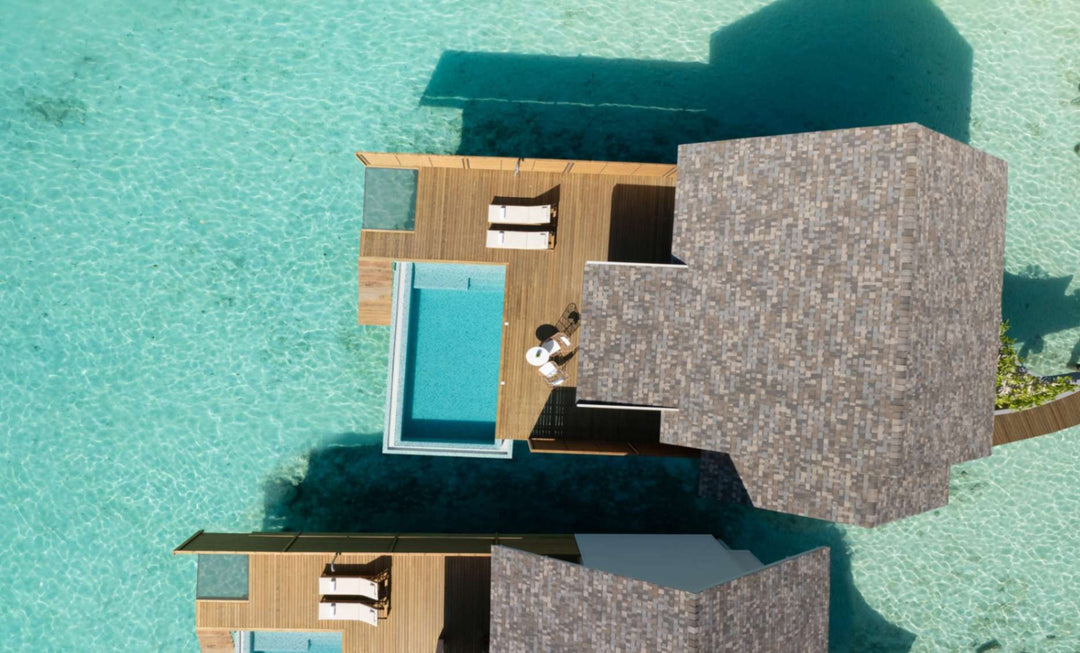An overwater villa at ananea Madivaru Maldives from directly above, pool and deck over clear shallow water