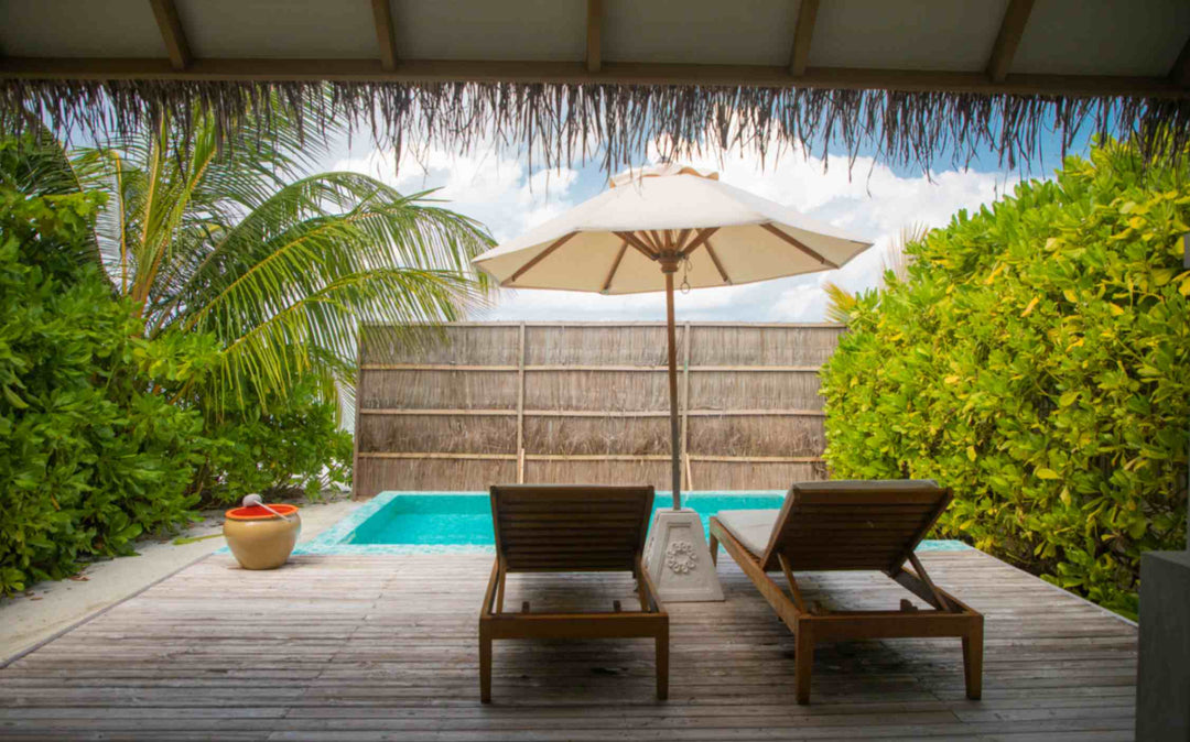 Sun Siyam Iru Veli, Dhaalu Atoll — beach villa pool and deck screened by a bamboo fence, with a palm overhead