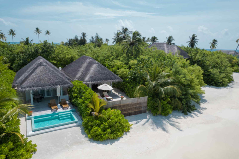 Sun Siyam Iru Veli from the air, over the thatched villa roofs, palms and the beach.