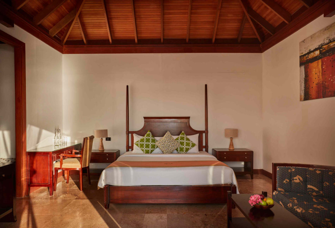 Sun Siyam Olhuveli, South Malé Atoll — Deluxe Water Villa bedroom under a timber vaulted ceiling, with a four-poster bed