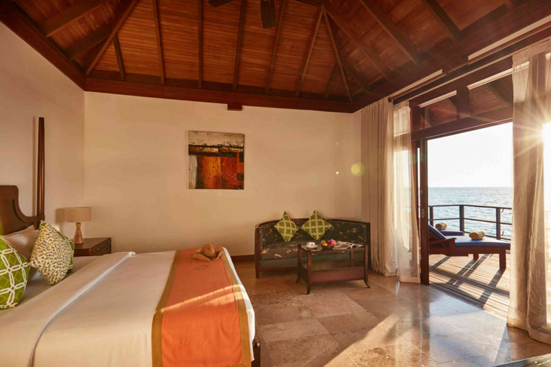 A Deluxe Water Villa bedroom at Sun Siyam Olhuveli with the doors open to the lagoon.
