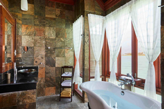 Sun Siyam Olhuveli, South Malé Atoll — slate-tiled bathroom with an oval bath beside the window