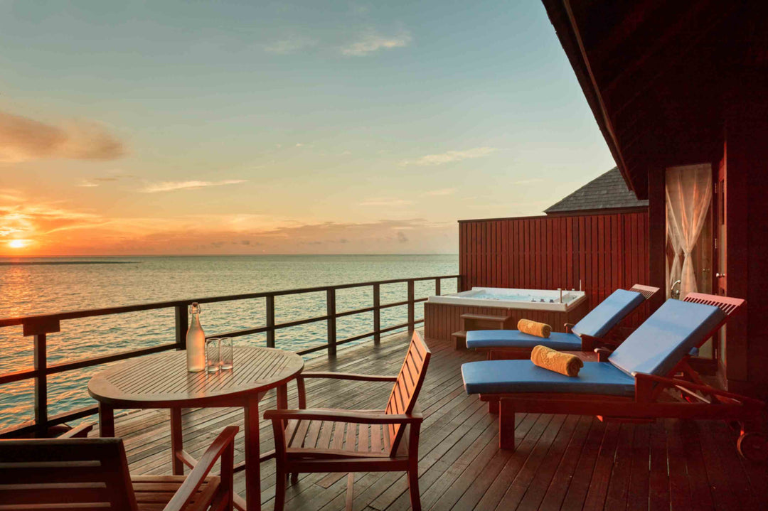 Sun Siyam Olhuveli, South Malé Atoll — the Prestige Jacuzzi Water Villa deck at sunset, with the jacuzzi and loungers